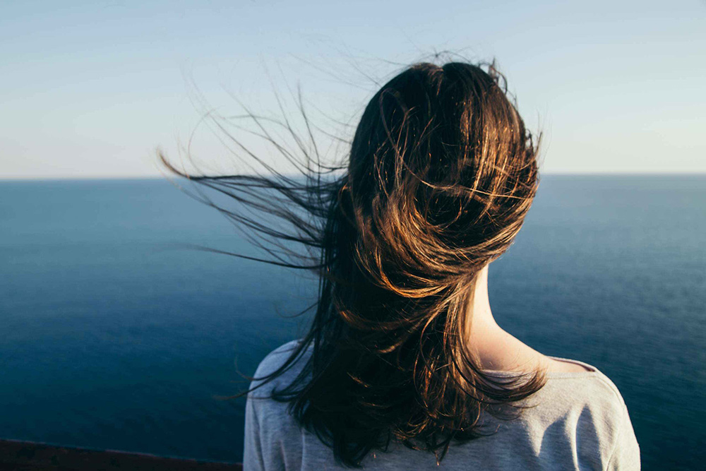 Girl looking at the ocean in the wind