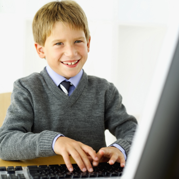 young male student in uniform at computer