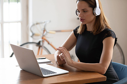 women working on a computer at a desk with headphone