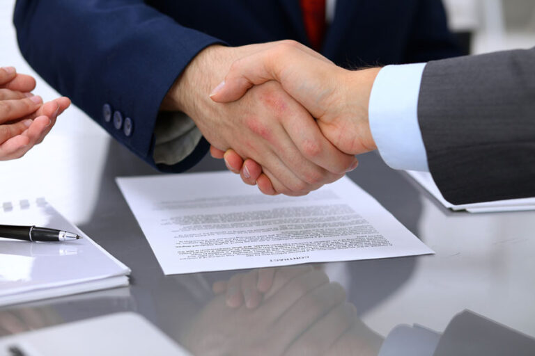 two men shaking hands over a contract