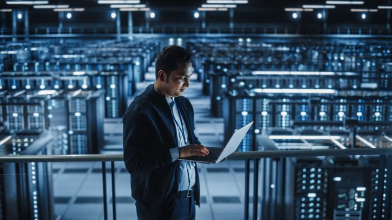 man in blue server room with laptop