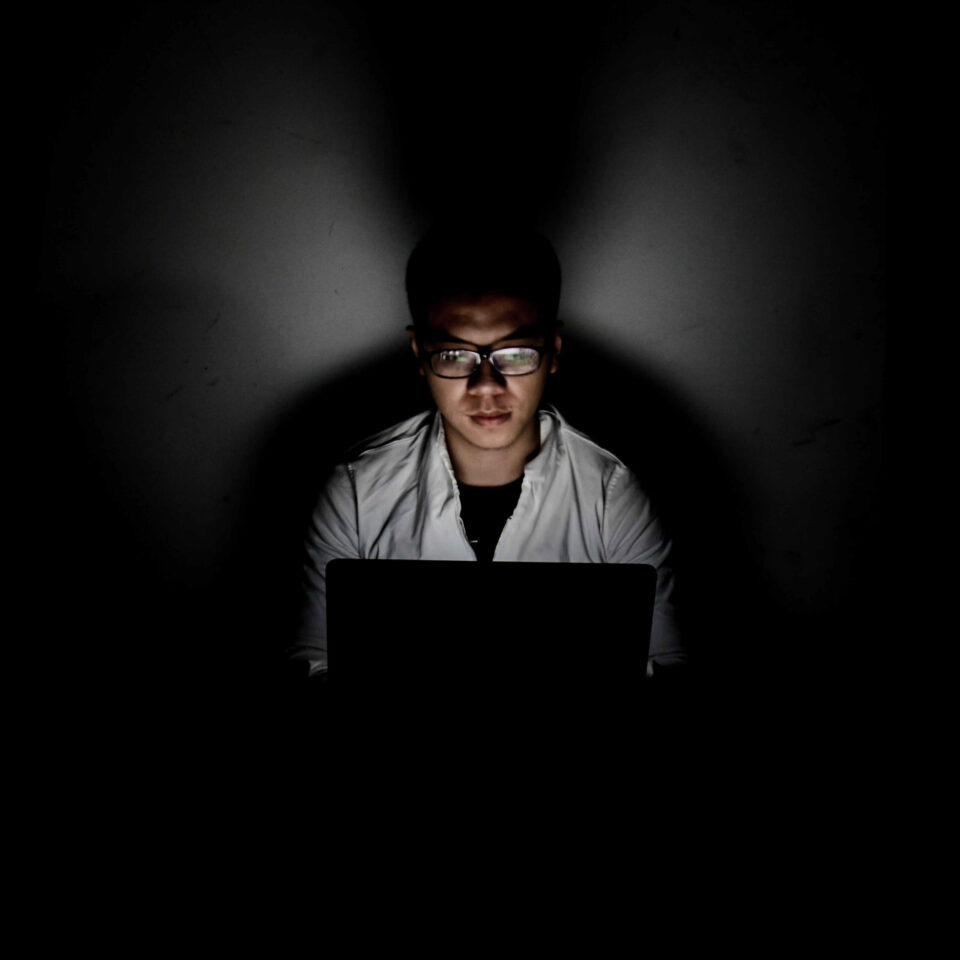 young person in dark on laptop