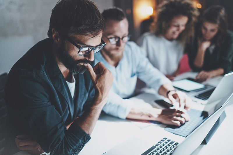 man with glasses using computer with colleague