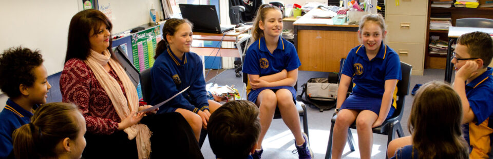 students and teacher sitting in a circle having a discussion