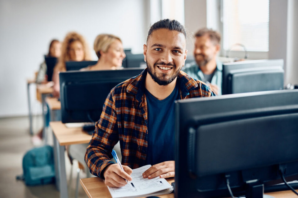 student in chequered shirt and beard working