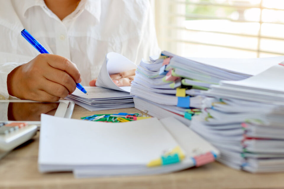 man marking lots of papers with colourful clips
