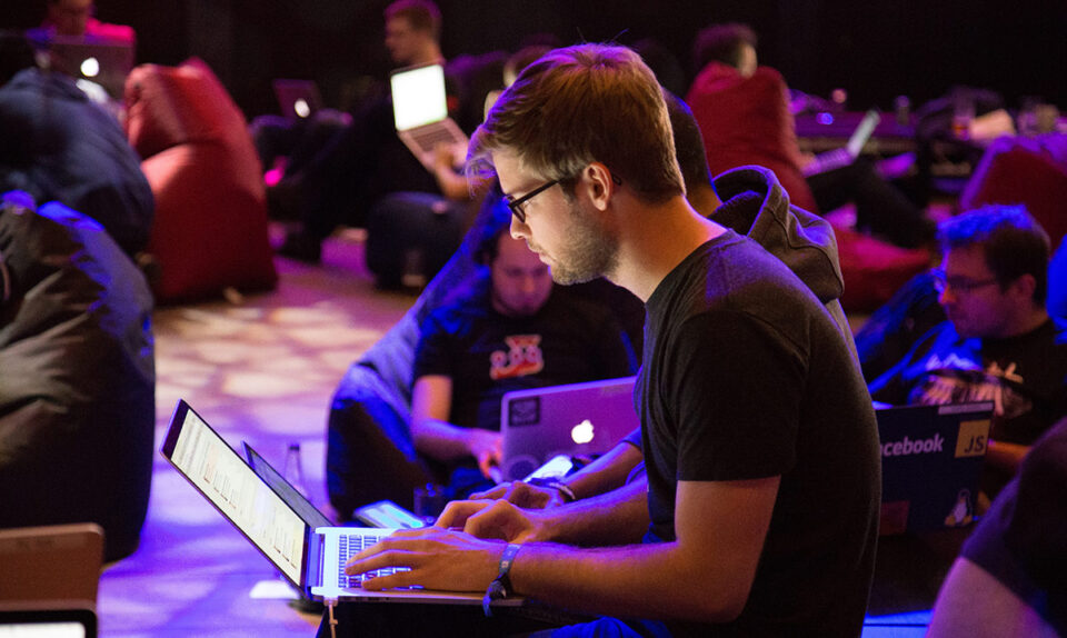 young man at tech conference working on laptop
