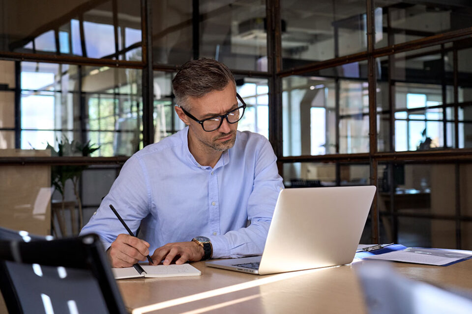 man in blue shirt and glasses working at computer