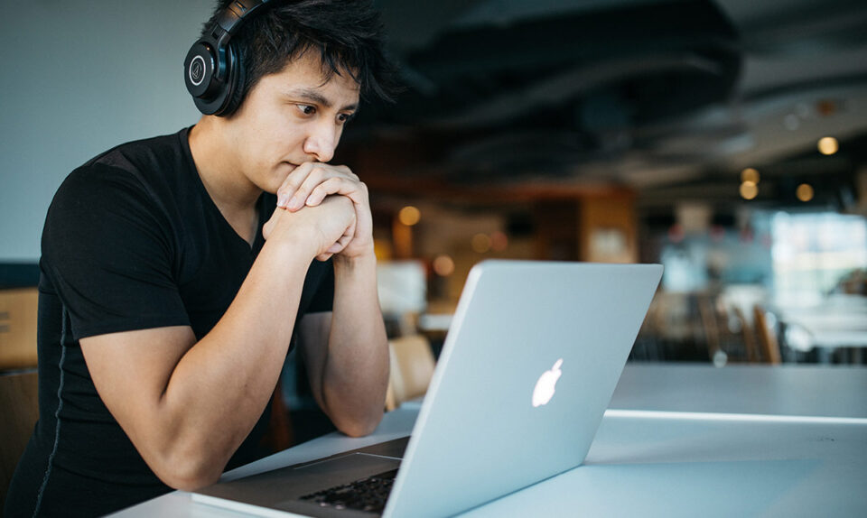 worried man with headphones looking at laptop