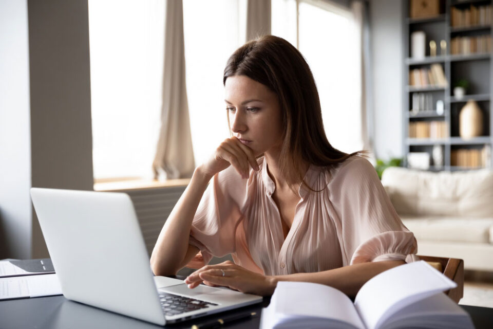woman with hand on chin working on computer