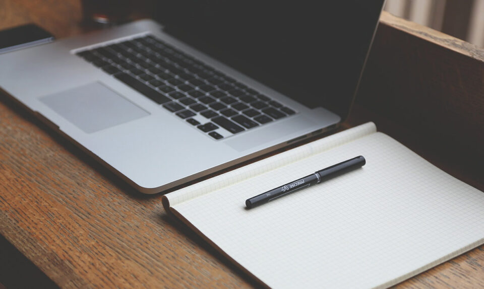macbook laptop, paper pad and pen for exams