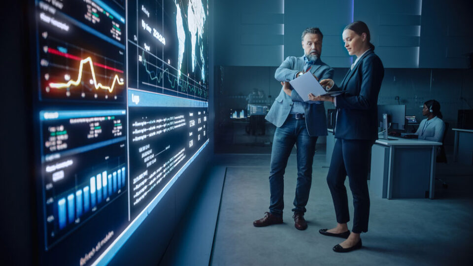 two men standing in front of huge wall dashboard
